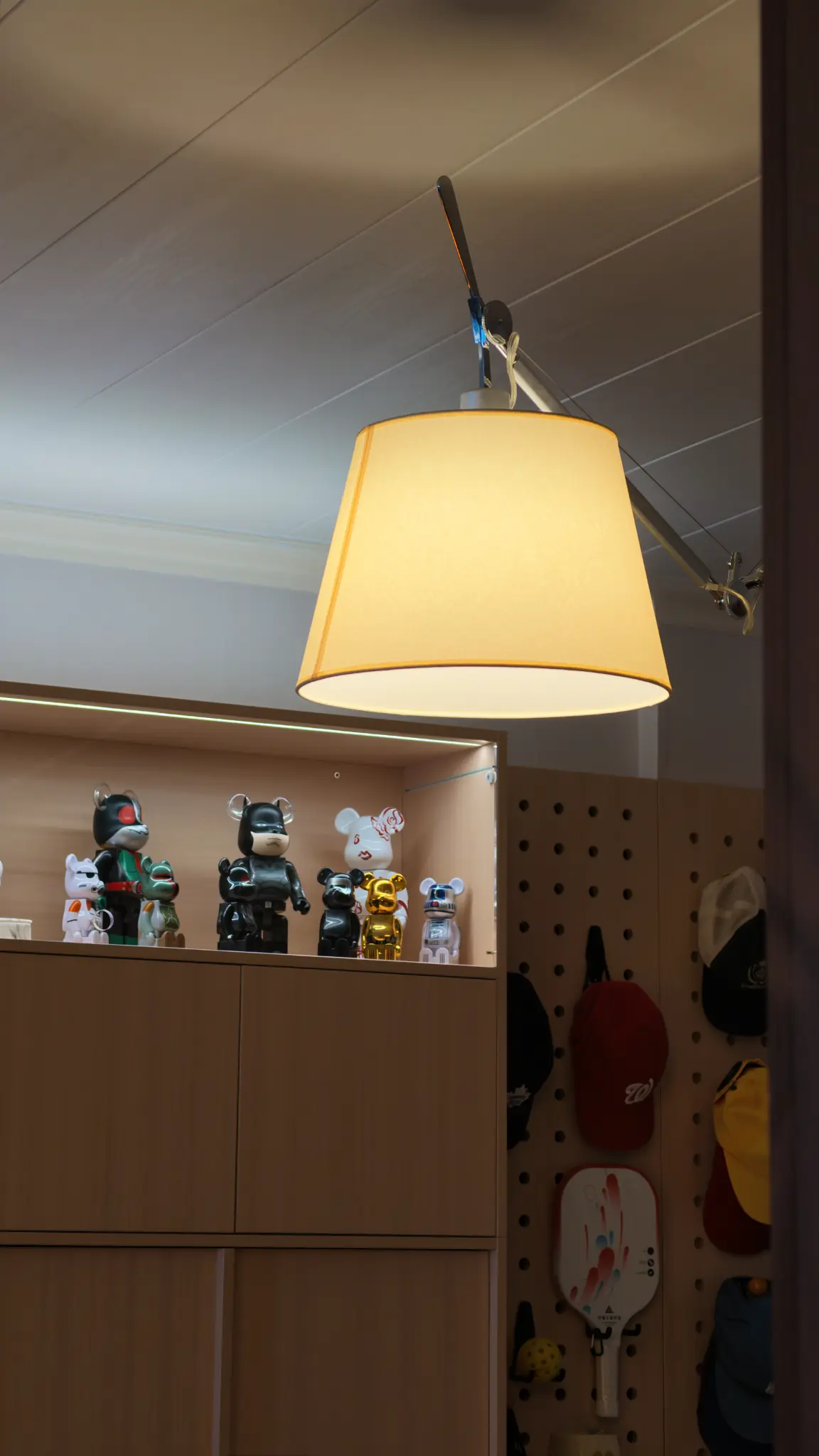 Warm pendant light over timber cabinetry, collectible figures and the entry pegboard.