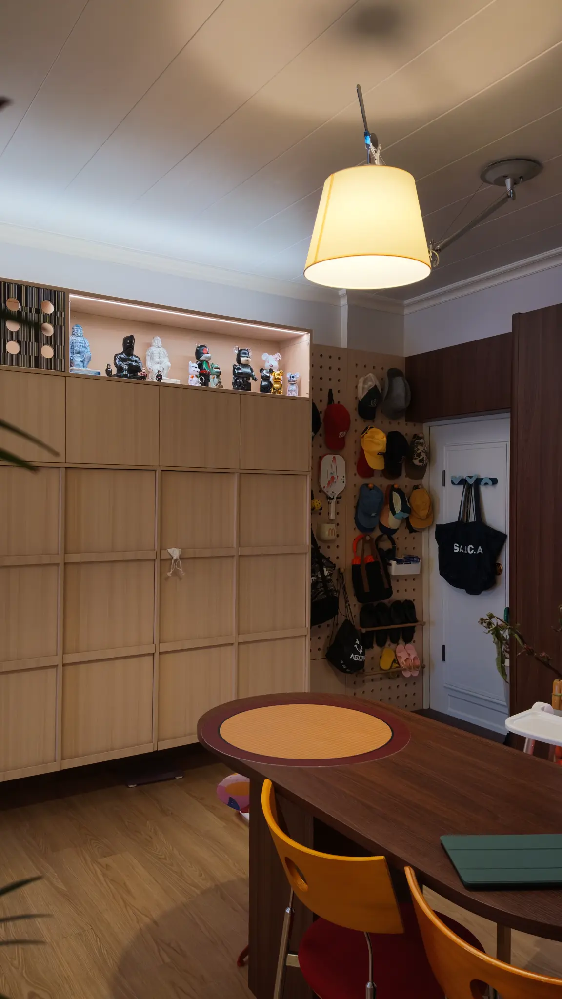 Dining table, yellow chairs, timber cabinetry and a wall of caps in Simon's home.