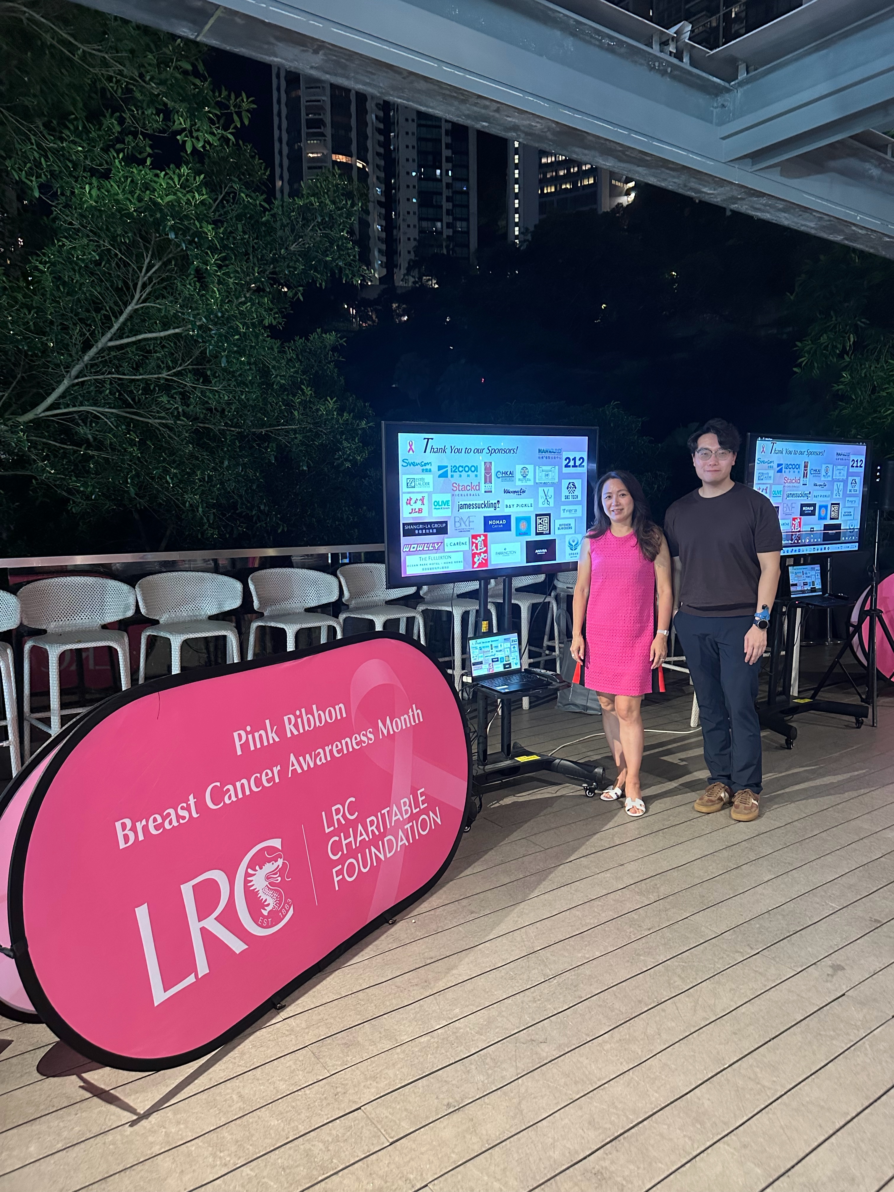 Owner-provided event photograph showing Pink Ribbon Breast Cancer Awareness Month signage and a sponsor display.